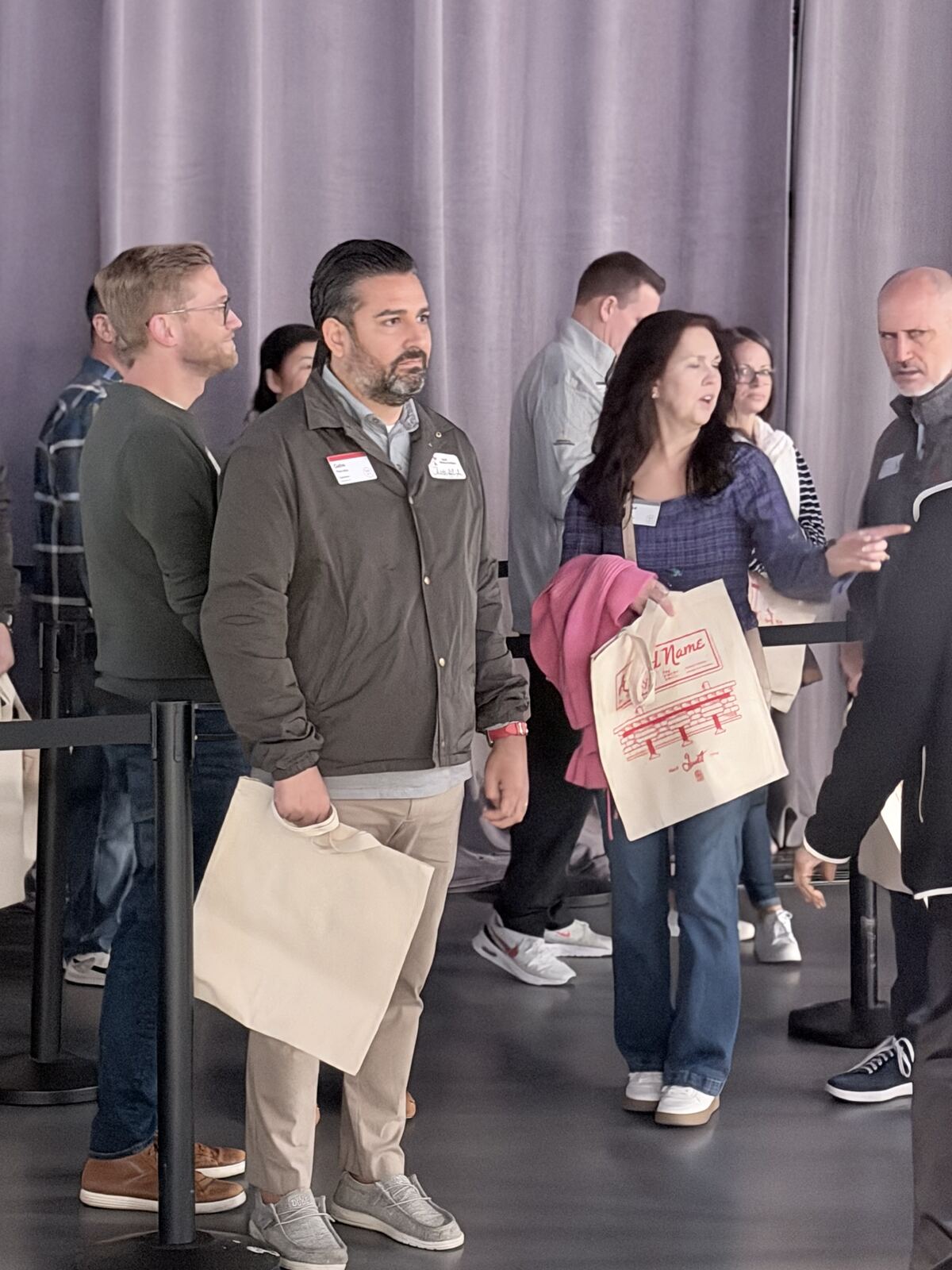 Group of professionals and attendees standing together at a corporate event holding branded merchandise